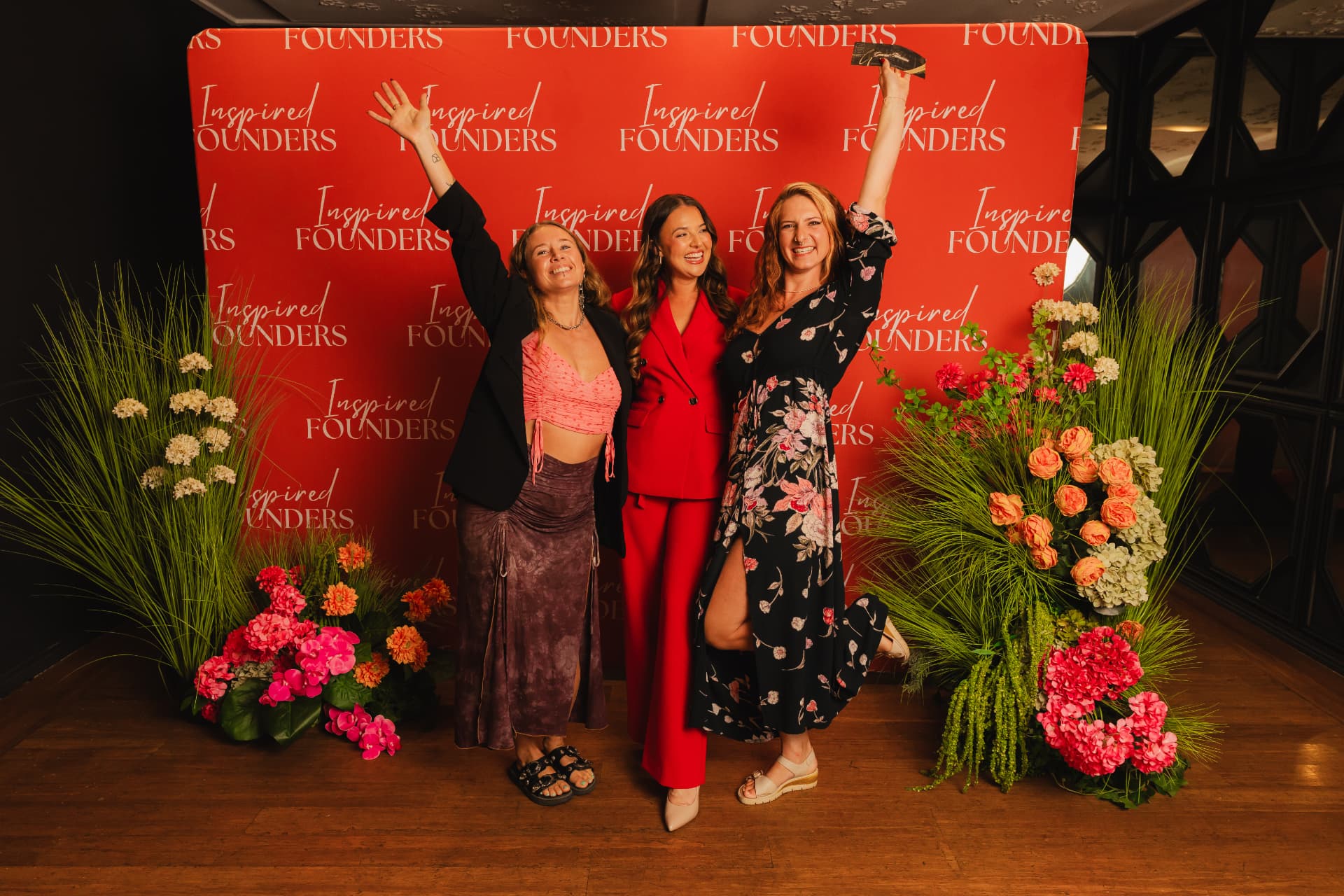 Three guests posing together on the Inspired Founders step and repeat